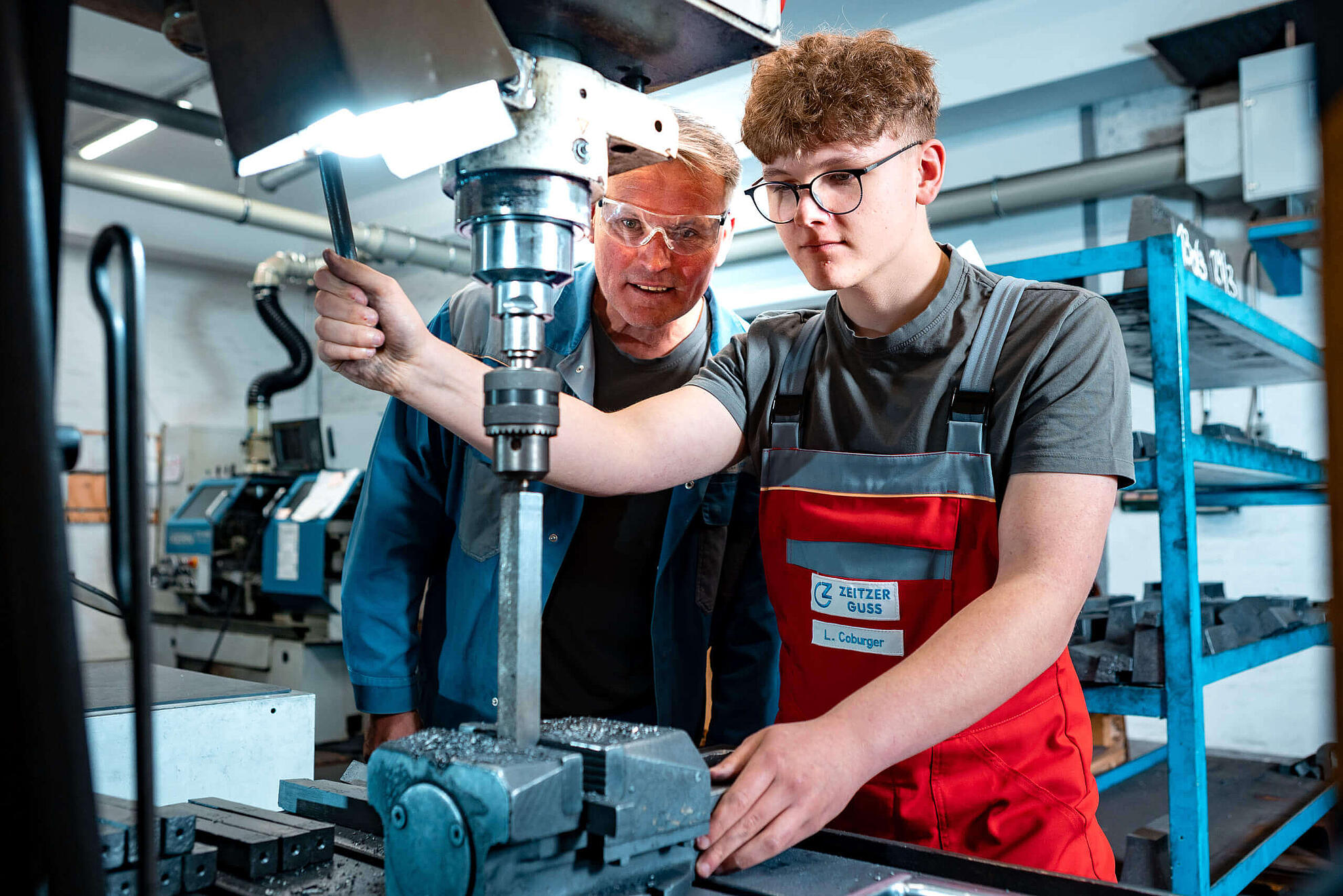 Produktionsmitarbeiter erklärt einem Azubi eine Arbeitsmaschine