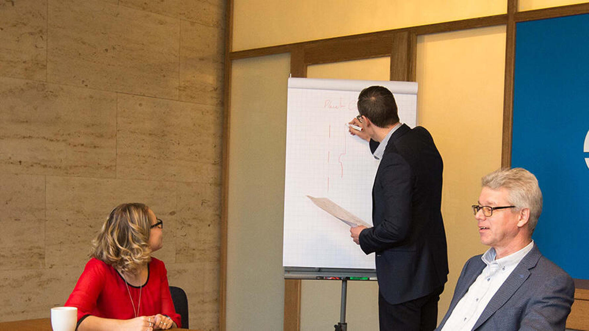Mehrere Personen sitzen bei einem Meeting zusammen und besprechen diverse Themen.